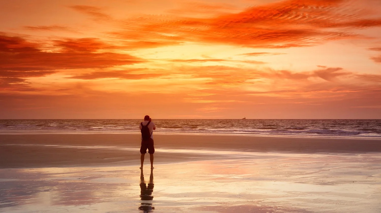 Wandelaar op het strand bij zonsondergang